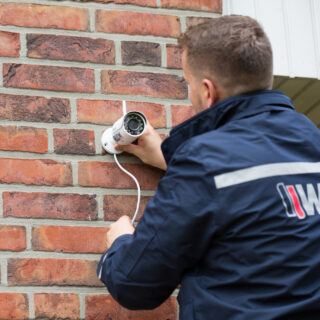 WSD Sicherheitsmitarbeiter installiert Überwachungskamera an Hauswand zur Einbruchprävention